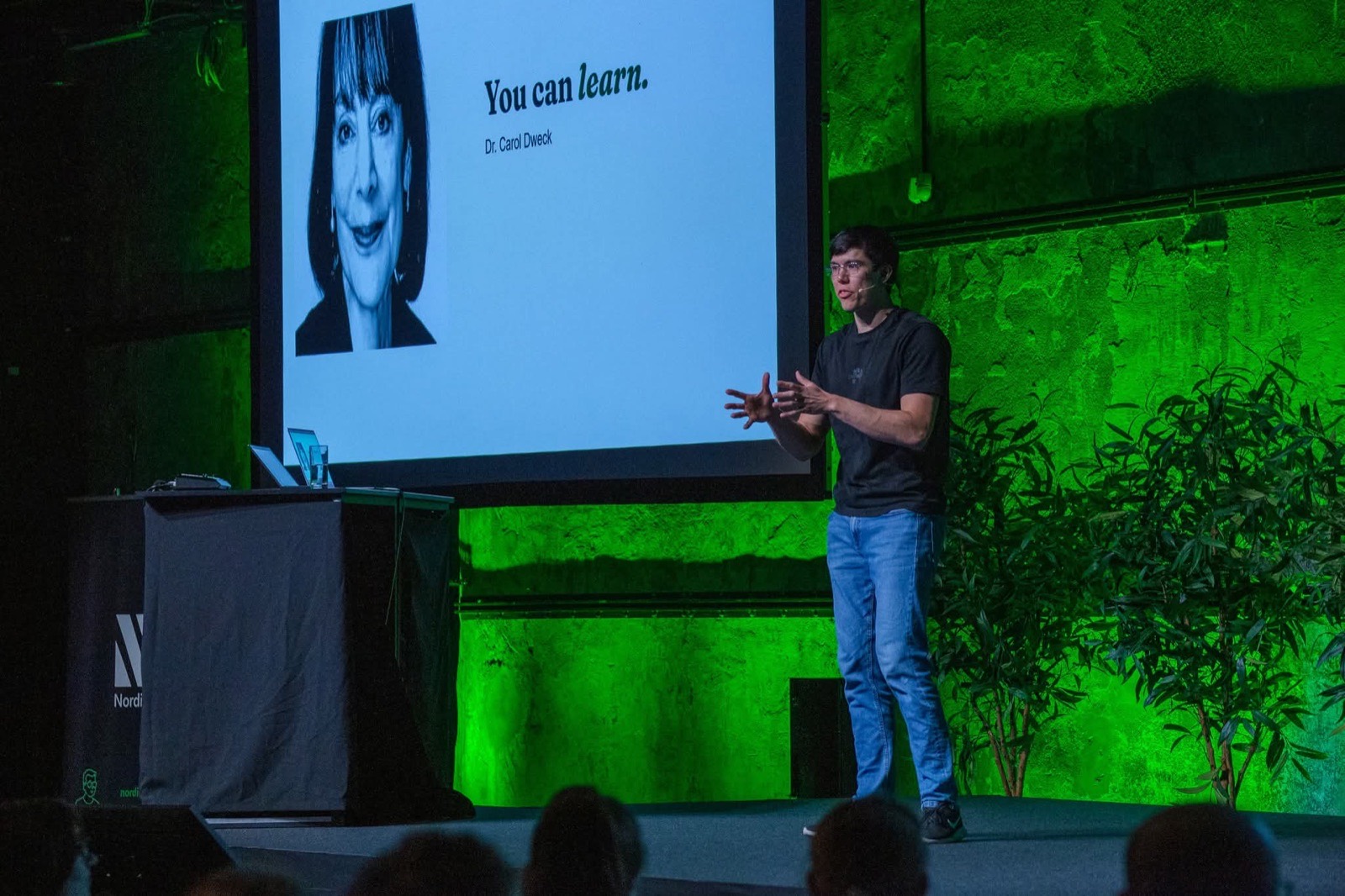 Jonas Hulthén on the green-lit Nordic Testing Days main stage in Tallinn beside a slide that quotes Dr. Carol Dweck, you can learn