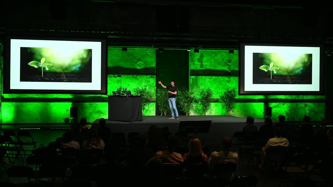 Jonas Hulthén alone on a large green-lit conference stage at Nordic Testing Days with two projection screens